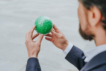 Businessman solving green color puzzle sphere