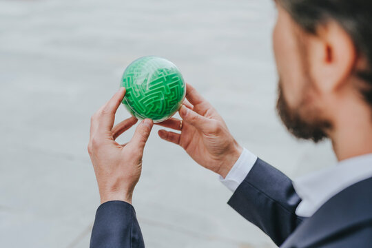 Businessman solving green color puzzle sphere