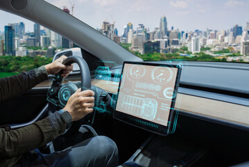 Person driving an electric car with a futuristic, high-tech dashboard and city skyline in the background.