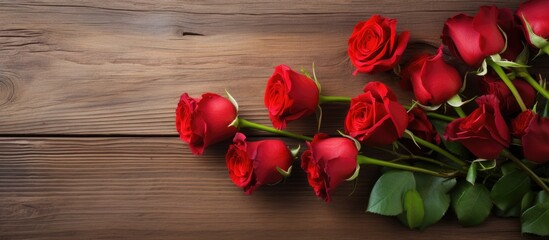 A beautiful arrangement of bright red roses displayed against a rustic wooden background with plenty of empty space for additional elements in the image