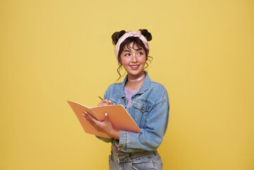 Portrait of happy smiling young Asian college student with notebook writing something ready to...