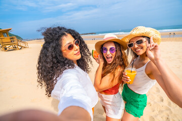 Selfie of multiethnic female friends enjoying summer on beach on vacation, outdoors smiling