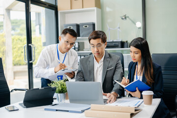 Happy Asian businesspeople while collaborating on a new project.  using a laptop and tablet