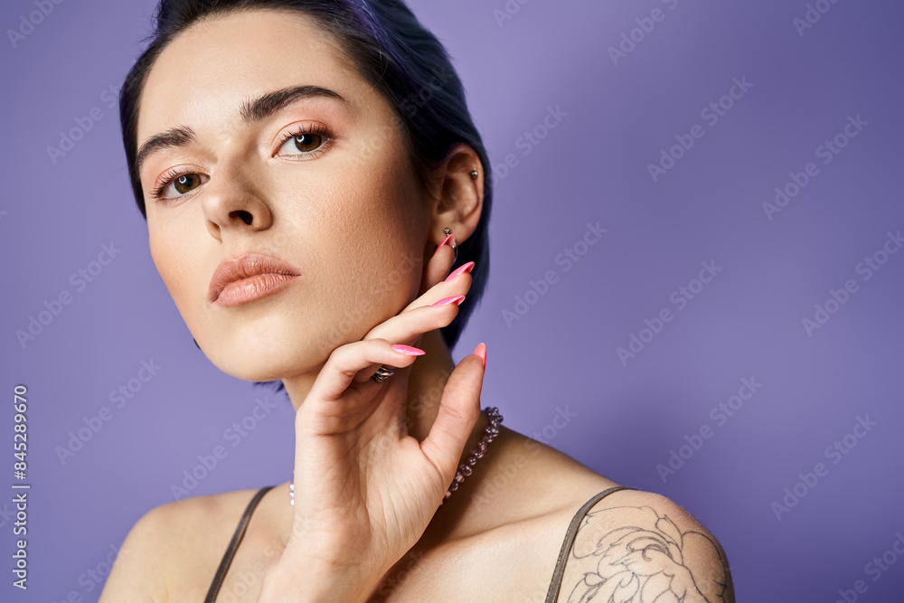 Wall mural A young woman with short blue hair showcases her arm tattoo while posing in a silver party dress in a studio setting.