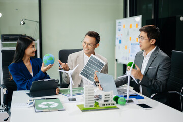 Group of businesspeople standing neare table looking at model of building from residential project. Green business company and Solar Energy