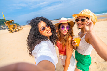 Three women are posing for a picture on the beach