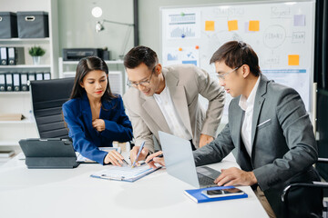 Office colleagues have a casual discussion. During a meeting in a conference room, a group of Asian business teem sit in the conference room