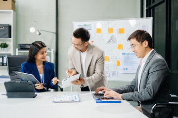 Office colleagues have a casual discussion. During a meeting in a conference room, a group of Asian business teem sit in the conference room