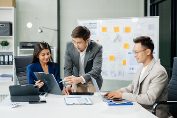 Office colleagues have a casual discussion. During a meeting in a conference room, a group of Asian business teem sit in the conference room