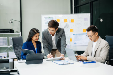 Office colleagues have a casual discussion. During a meeting in a conference room, a group of Asian business teem sit in the conference room