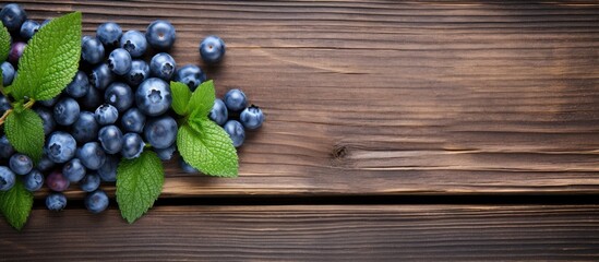 Obraz premium A top view of a fresh and natural blueberry with mint on a wooden table This berry is organic and a good source of vitamins The image provides copy space for text