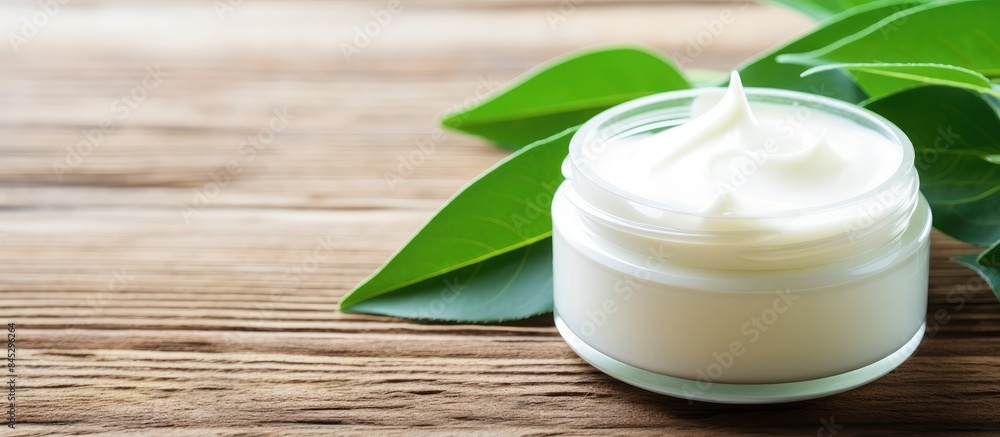 Poster On a bright wooden table there is a white cosmetic cream with leaf buds in the background creating a visually appealing image with empty space. Creative banner. Copyspace image
