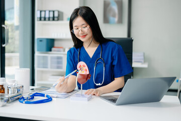 Confident young Asian female doctor in white medical uniform sit at desk working on computer....