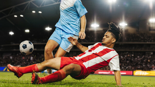 Intense football tackle during professional football match at a full stadium