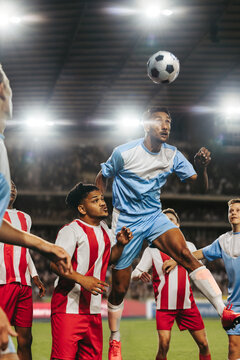 Intense football match with players going for a header at a night stadium