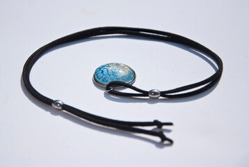 Naszyjnik na rzemyku z ręcznie malowanym żółto - niebieskim oczkiem na białym izolowanym tle