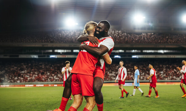Professional football players celebrating a goal in a crowded stadium