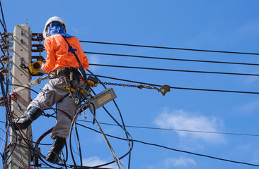 Electrician with safety equipment and work tools is installing cable lines and electrical system on...