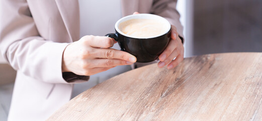 コーヒーを飲みながらスマートフォンを操作している若い女性　ビジネスイメージ