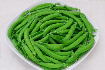 Green peas in a plate on white background. Fresh peas in bowl. Bowls of vegetables.