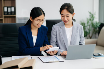 Two business workers talking on the smartphone and using laptop at office