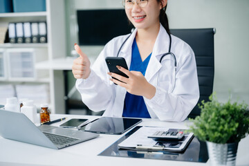Medical technology concept. Asian Doctor working with mobile phone and stethoscope in office