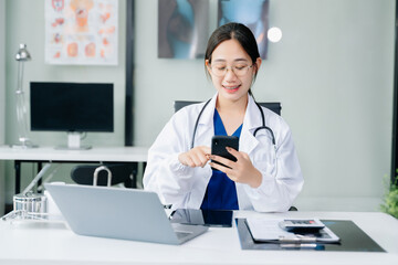 Medical technology concept. Asian Doctor working with mobile phone and stethoscope in office