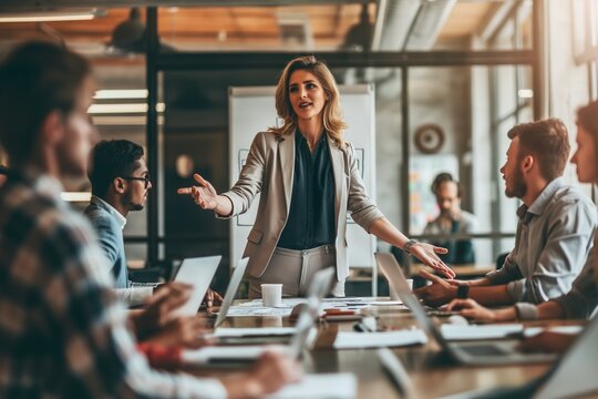 Female manager standing at the head of the table with open arms during a meeting