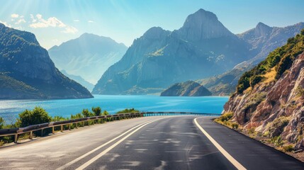 Empty highway on the background of steep mountain peaks, sea coast on one side of the road, blue water, clear sunny day, bright rays