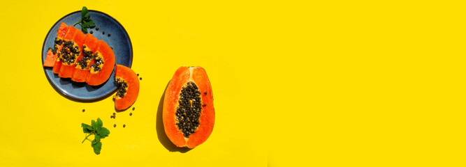 slices and half of papaya fruit on the yellow background , copy space, banner, isolated, flat lay