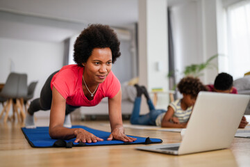 Happy african american fit woman working out with online traning at home. Sport technology concept