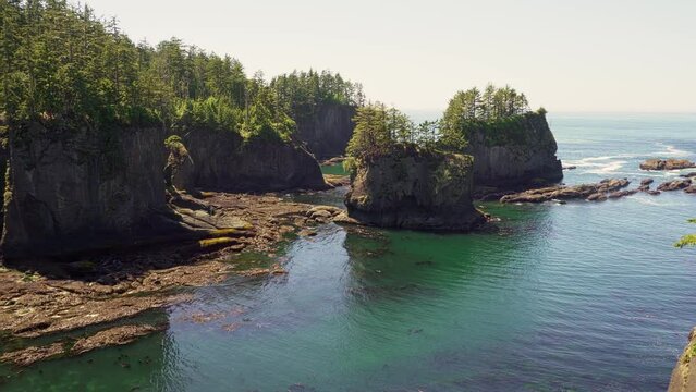 Pan right of sea stacks and rocky coastline at Cape Flattery, located on the Makah Reservation in the Olympic Peninsula, with forested cliffs and blue ocean. 4K UHD video.