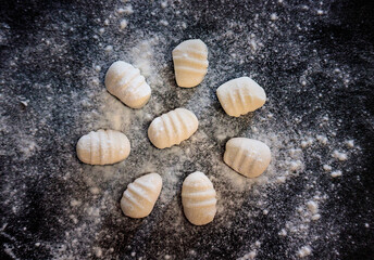 gnocchi on black background with flour, view from above
