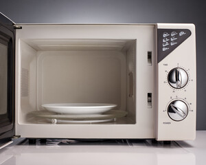 Obraz premium White open microwave with plate on gray background