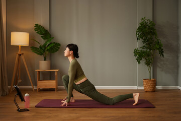 Beautiful Asian woman using laptop while practicing yoga at home