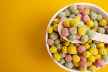 Colored breakfast cereals in a bowl with a spoon on a bright background. Breakfast concept, colorful cornflakes, top view Sweet snack