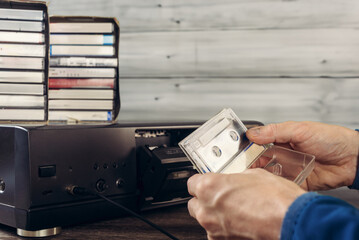Man taking tape cassette out of case to insert it into vintage tape recorder. Vintage charm:...