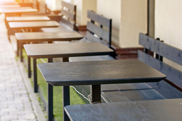 Empty summer terrace with wooden tables and seats, serene and tranquil outdoor dining area.