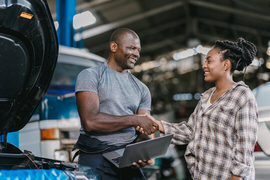 Happy customer dealing hand shaking with mechanic man fix car problem. Satisfied garage car service.