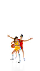 Vertical image of two competitive women, basketball players in motion with ball during game, training isolated on white studio background. Concept of sport, active lifestyle, competition, dynamics