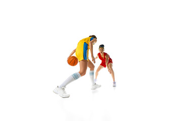 Focus on the Court. Two young women in red and yellow uniforms competing with each other, playing basketball isolated on white background. Sport, active lifestyle, competition, game, dynamics concept