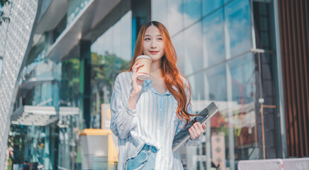 Fototapeta premium A woman with red hair is holding a cup of coffee and a laptop