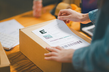 startup young female small business owners attaching shipping labels to cardboard boxes or parcels for delivery of customer orders-concept shopping online.