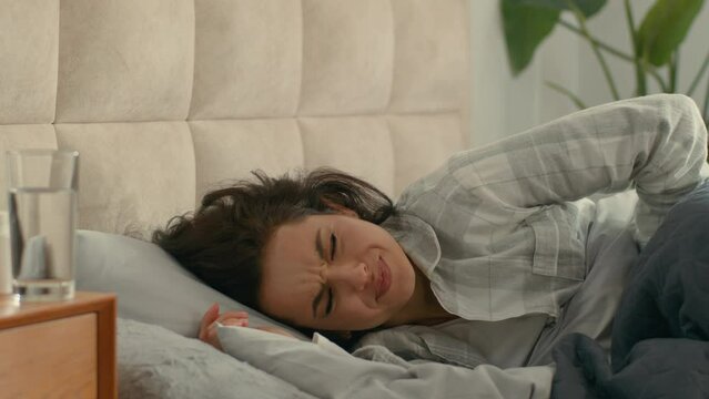 Woman lying on bed bedroom clutching stomach suffering female girl abdomen gastrointestinal painful digestion disease menstruation unwell ill hurting unhealthy menses ache pressure belly discomfort