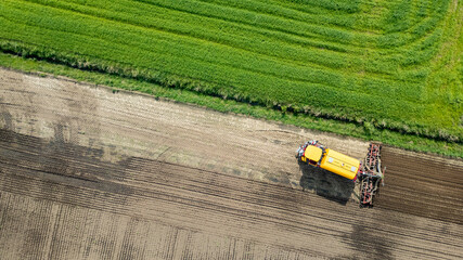 A drone captures aerial footage of farmland with modern tractor equipment working on crops,...