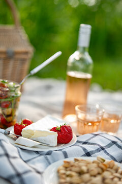 Delicate camembert cheese and chilled rose wine on a summer picnic. Vertical close-up with short depth of field.