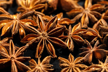 Close up Anise star food background, fragrant spices dry brown anise seeds on black background, natural organic seasoning texture, dark colored photo, selective focus