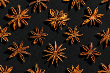 Anise stars background food pattern, top view close up photography fragrant spices dry anise seeds on black background, natural organic seasoning texture, dark colored minimal flat lay