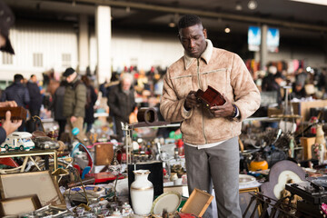 Ordinary Afro-American guy considers things sacond hands on flea market