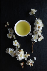 Japanese green tea and Ume (apricot) flowers on a black granite board background. Japan.